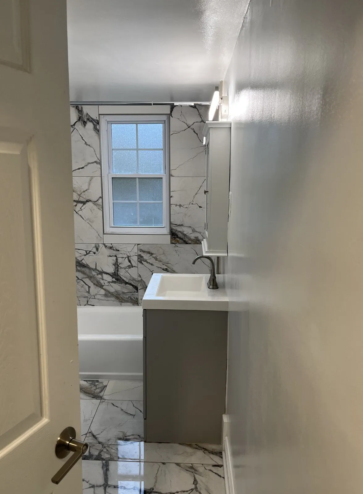 Bathroom remodel with marble-look tile, new vanity, and updated fixtures